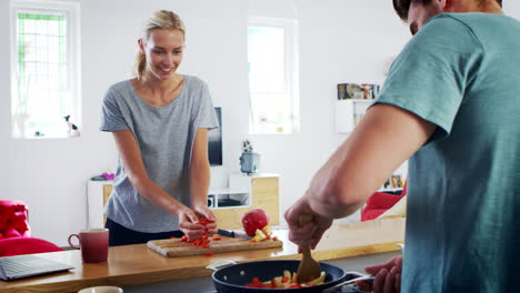 una joven pareja preparando comida juntos en una cocina moderna
