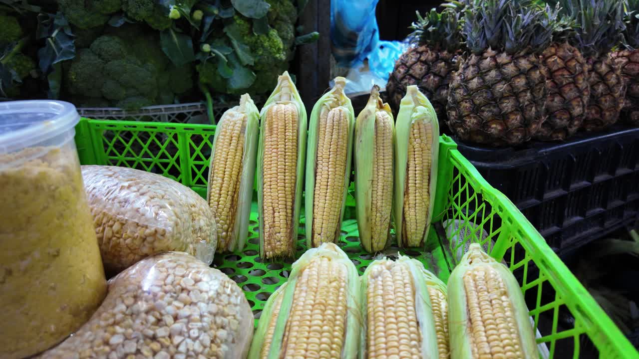 Close-up of corn ears, kernels, and jar on a market stall in Caracas.
