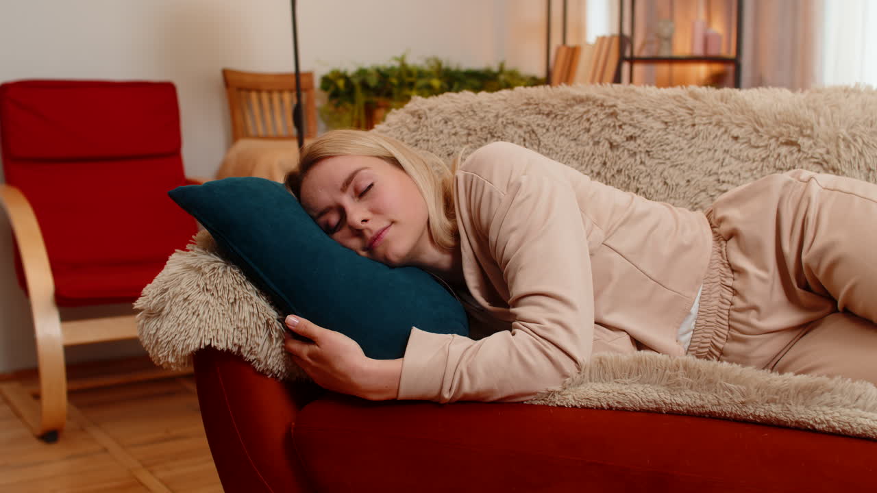 Adult woman falling asleep on sofa at home after work showing tiredness peaceful emotional relief