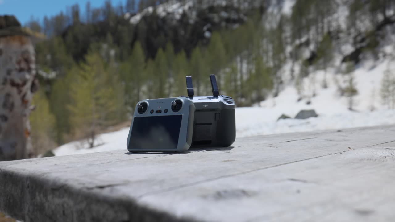 Two DJI drone controllers outdoors on wooden picnic table with no person