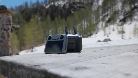 two dji drone controllers outdoors on wooden picnic table with no person
