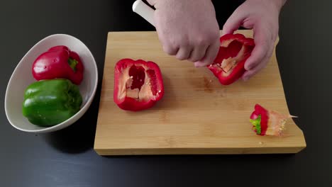 la mano del chef corta y limpia el pimiento rojo.