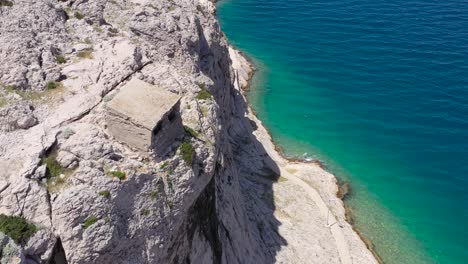 Ovejas-Entran-Al-Refugio-En-El-Acantilado-Rocoso-En-La-Isla-De-Otok-Pag-Croacia-Cerca-Del-Pueblo-De-Metajna,-Vista-Aérea-Del-Sobrevuelo