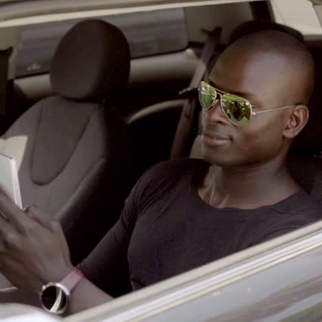 Handsome-black-man-seated-in-car-with-teléfono