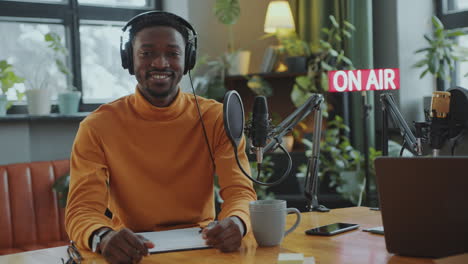 portrait of smiling african american podcast host in recording studio