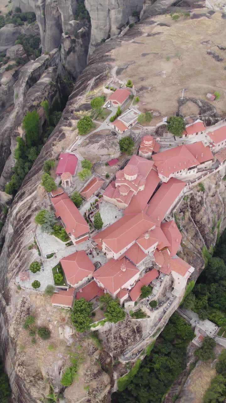 Vertical topdown aerial shot circling the Monastery of Great Meteoron in Meteora, Greece, highlighting its architecture and cliff-top location