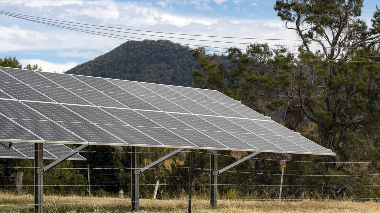 timelapse de 4k de nubes moviéndose proyectando sombras sobre paneles solares en una granja en el campo australiano
