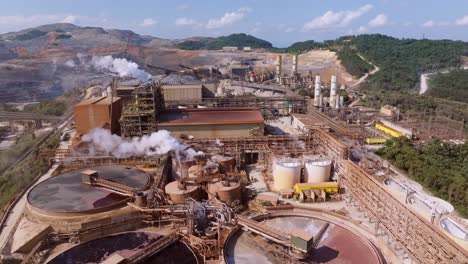 aerial dolly in over large steel factory with pipes, chimneys in rural landscape