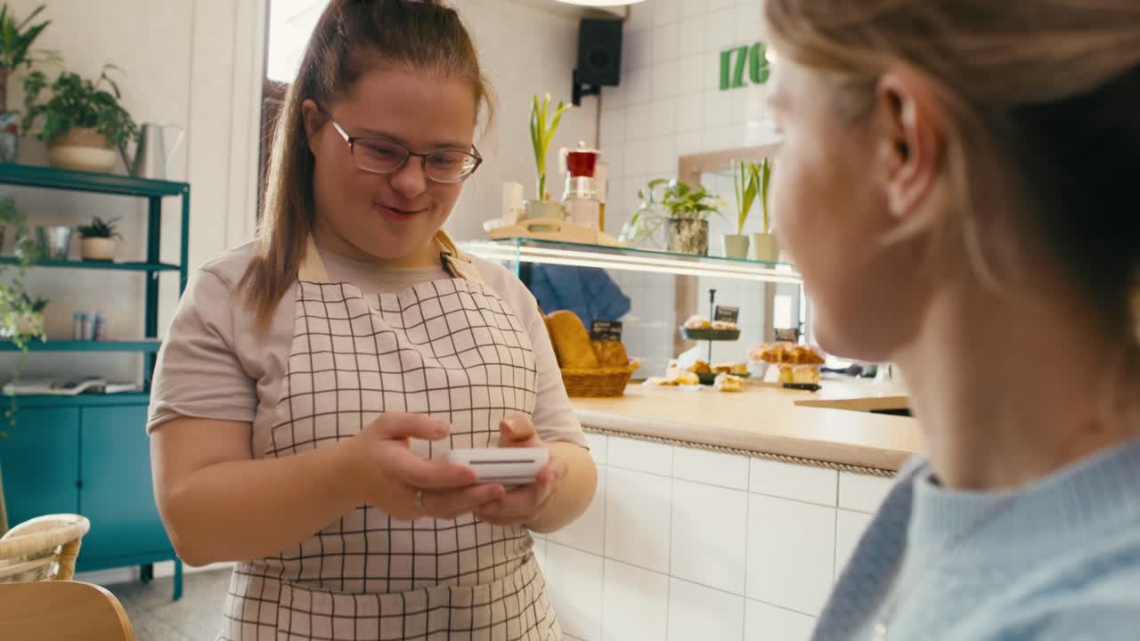 hombre caucásico con síndrome de down aceptando el pago sin contacto en el café