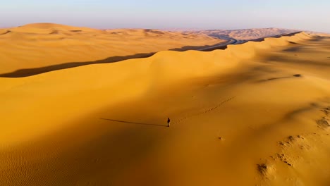 aerial view of a man walking on dunes during the sunset, u.a.e.