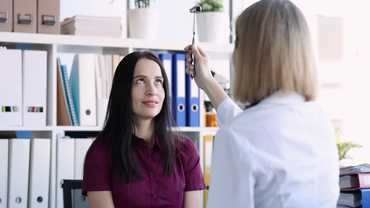 Doctor performs an eye examination on a patient using a reflex hammer