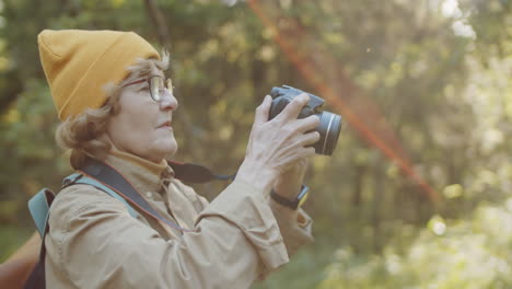 senior woman taking photos in the forest