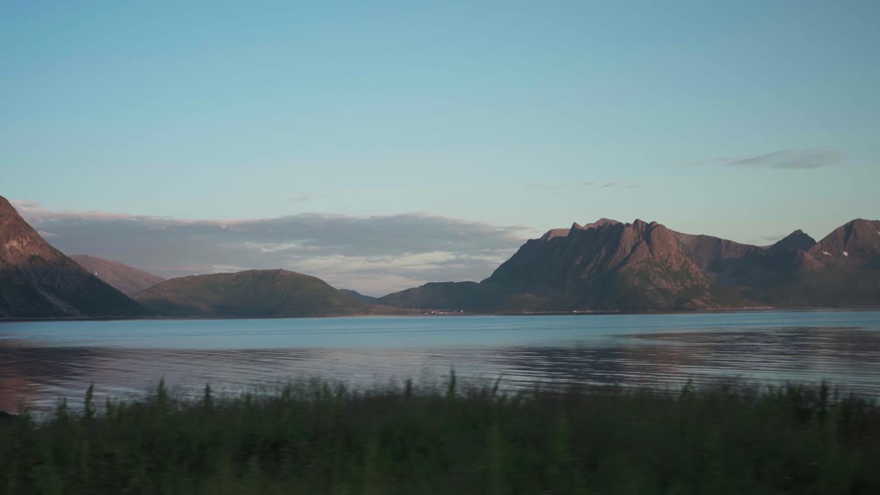 viajando por la costa con majestuosas montañas en el fondo cerca del pueblo de flakstad en senja, noruega