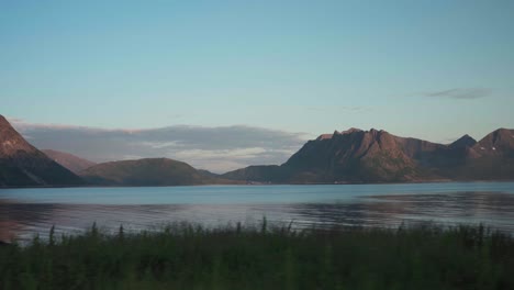 Viajando-Por-La-Costa-Con-Majestuosas-Montañas-Al-Fondo-Cerca-Del-Pueblo-De-Flakstad-En-Senja,-Noruega