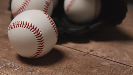 close up studio baseball still life with balls in catchers mitt on wooden floor 4