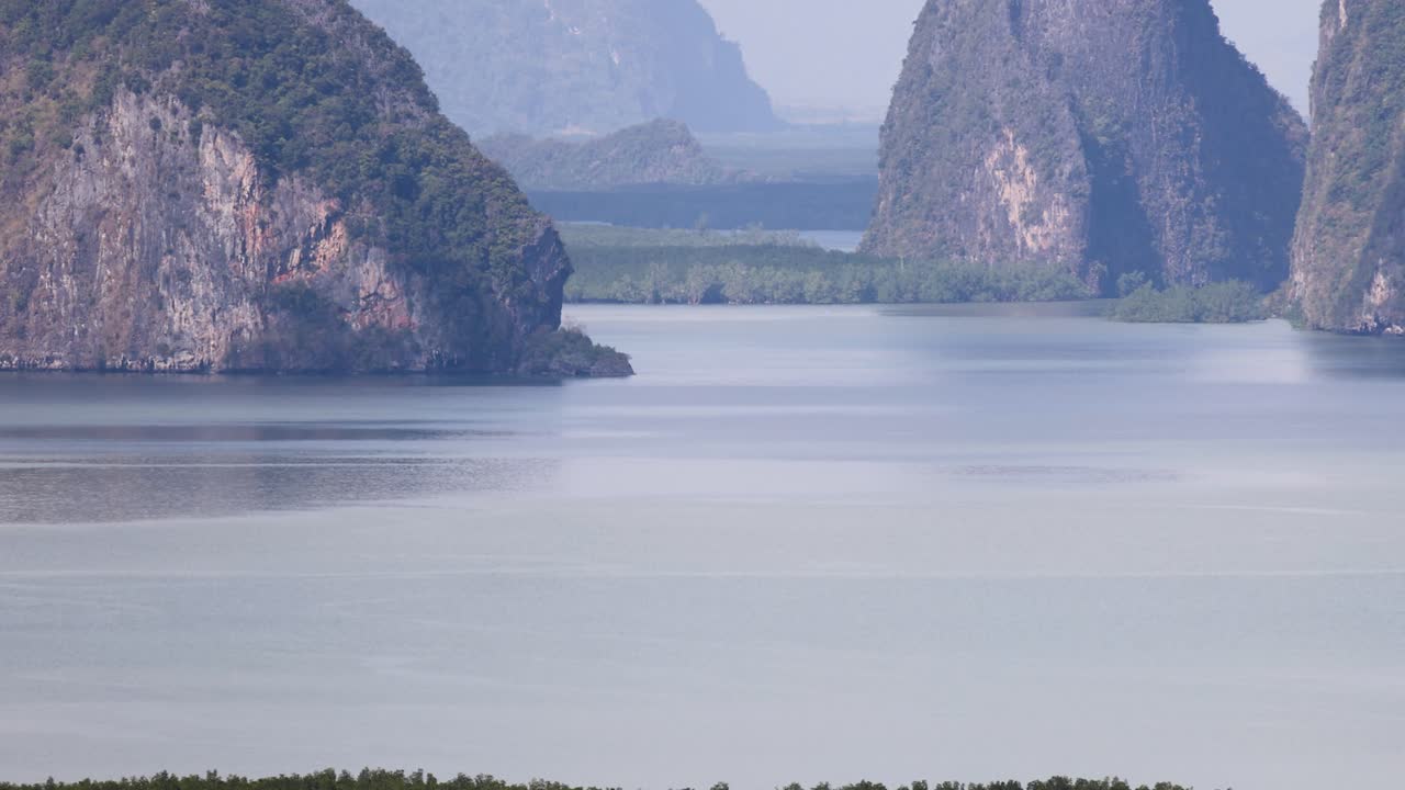 A tranquil view of Phang Nga Bay with limestone cliffs and calm waters under soft daylight