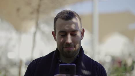 Cheerful-young-man-holding-modern-smartphone