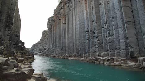 studlagil turquoise river flowing through a spectacular canyon of basalt rock formations