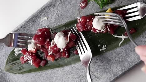 people using forks sharing tasty red tuna plate, spanish food