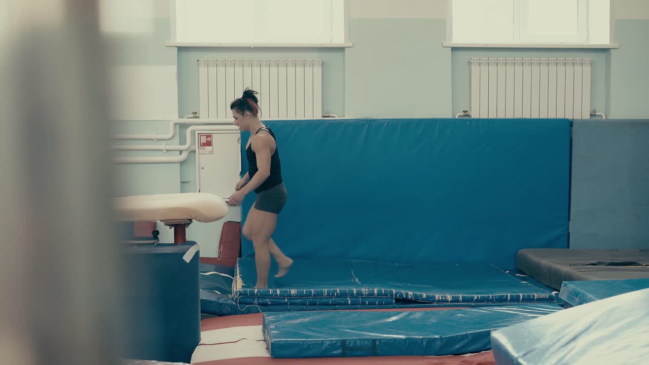 체육관에서 젊은 운동선수 소녀가 뒤로 돌고 있습니다.