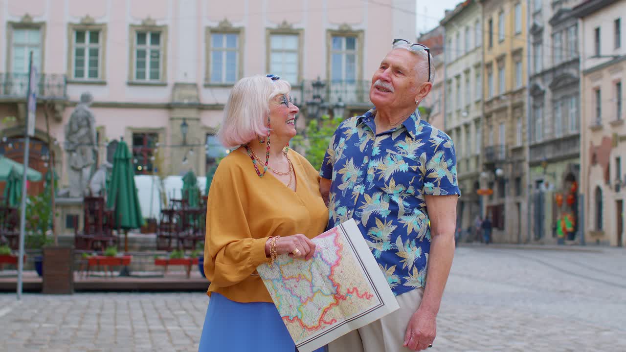 Anziani turisti eleganti, un uomo e una donna, che si godono una conversazione per strada, tenendo una mappa cartacea nel centro storico.