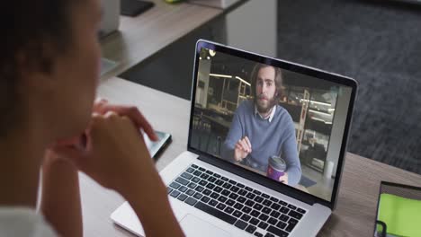 mujer afroamericana haciendo una videollamada en una computadora portátil con un colega masculino en la oficina