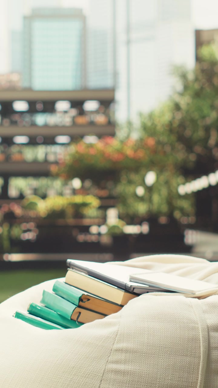 Vertical Video Stacks of books placed on beanbag on sunny campus lawn