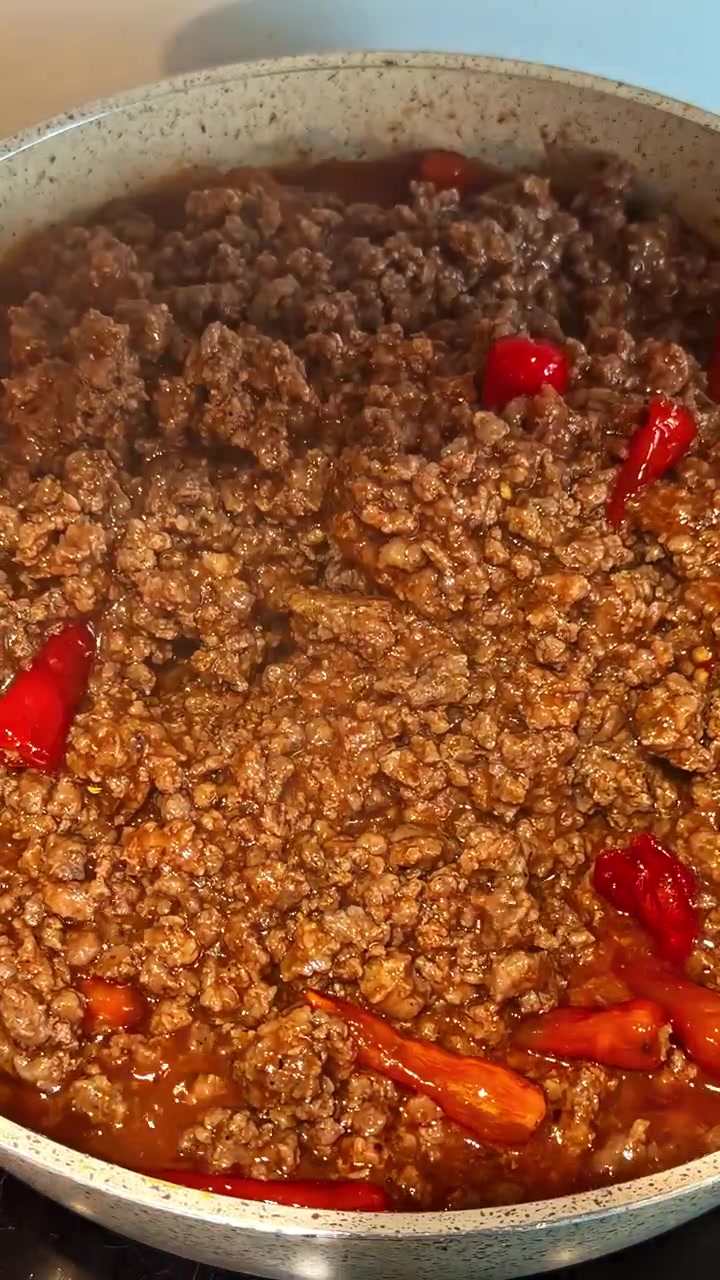 Delizioso ragù alla bolognese fatto in casa che sobbolle in una pentola con peperoncini rossi freschi per un pasto piccante