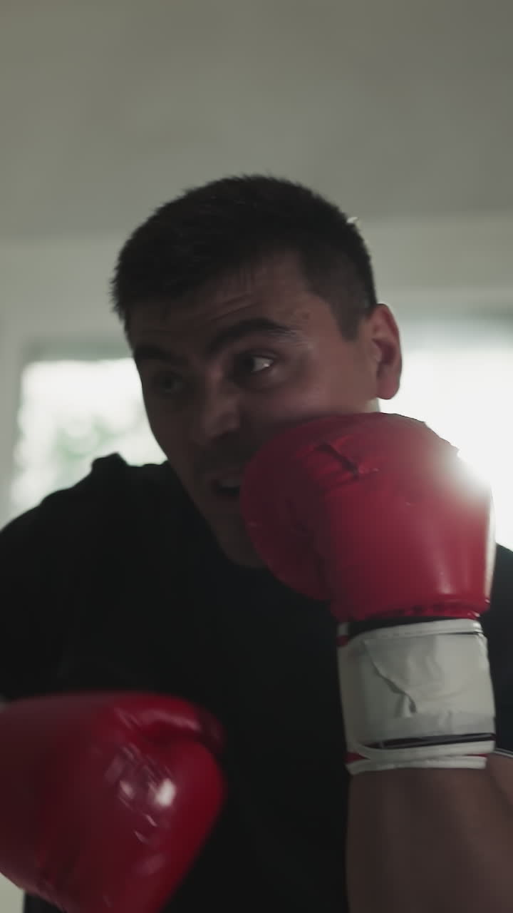 hombre fuerte golpea la bolsa de boxeo por los brazos con guantes en el gimnasio. maestro de artes marciales golpea el equipo en el club de boxes en cámara lenta. rendimiento de entrenamiento de combate