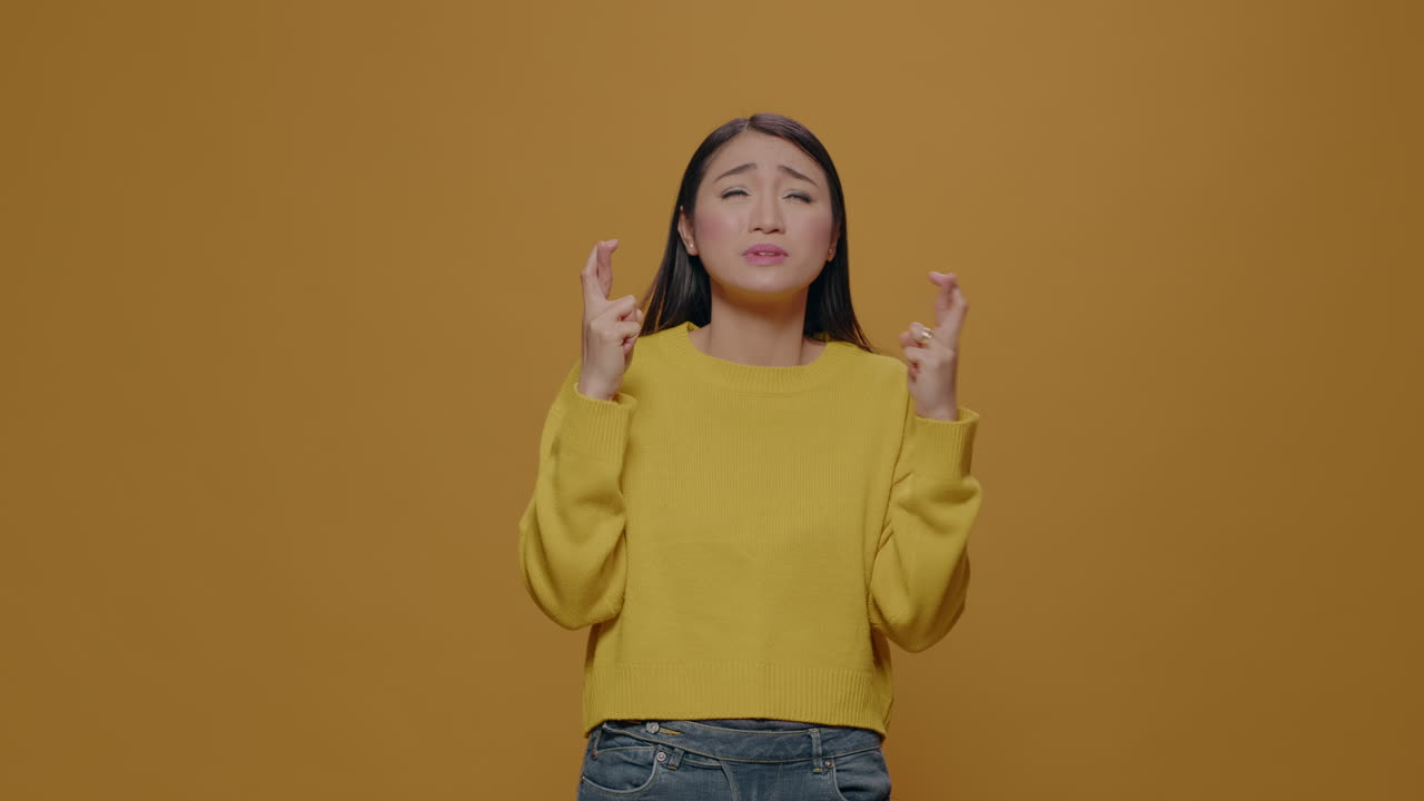 Positive adult doing praying sign with fingers crossed