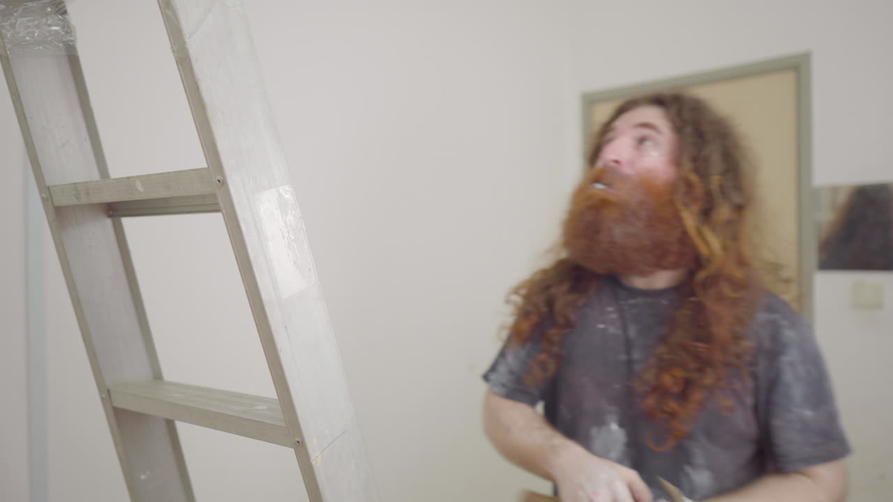 hombre de reparación de viviendas desciende la escalera y escupe clavos de su boca