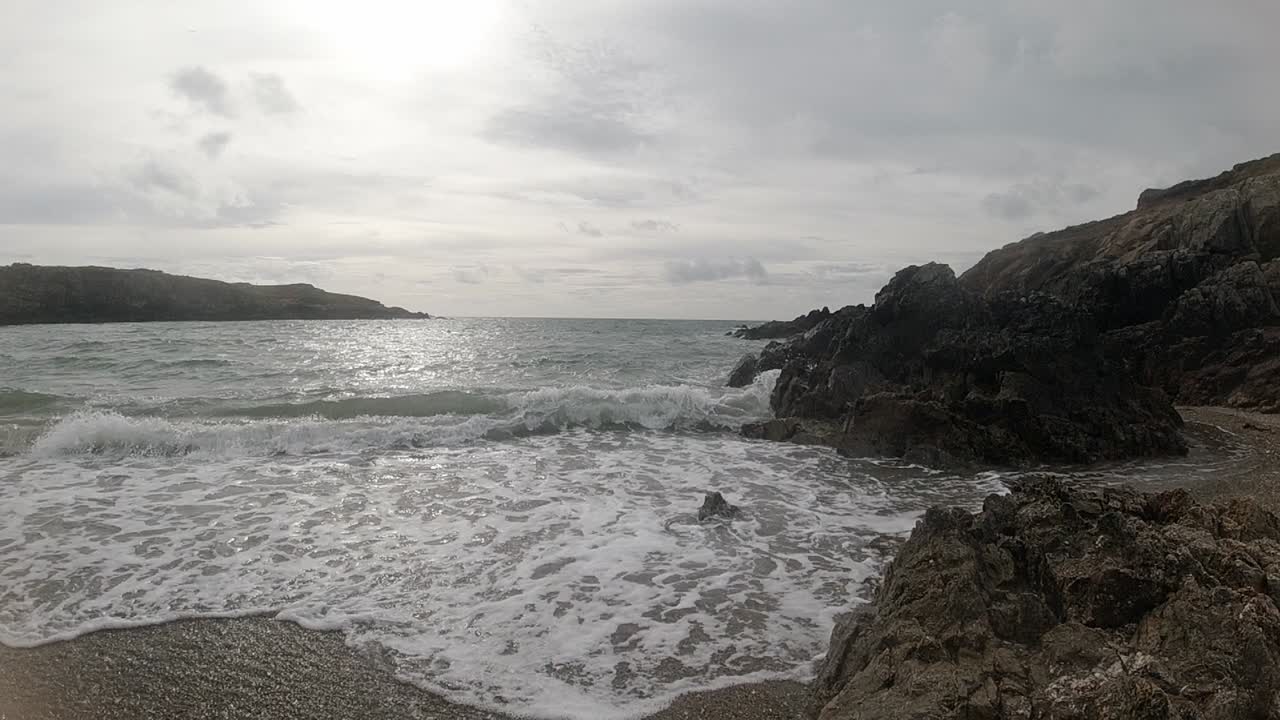 olas del océano pacíficas en cámara lenta rompiendo contra la escarpada costa galesa al amanecer