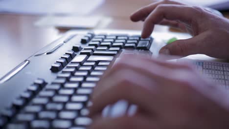 Hands typing on a black keyboard in a well-lit office setting