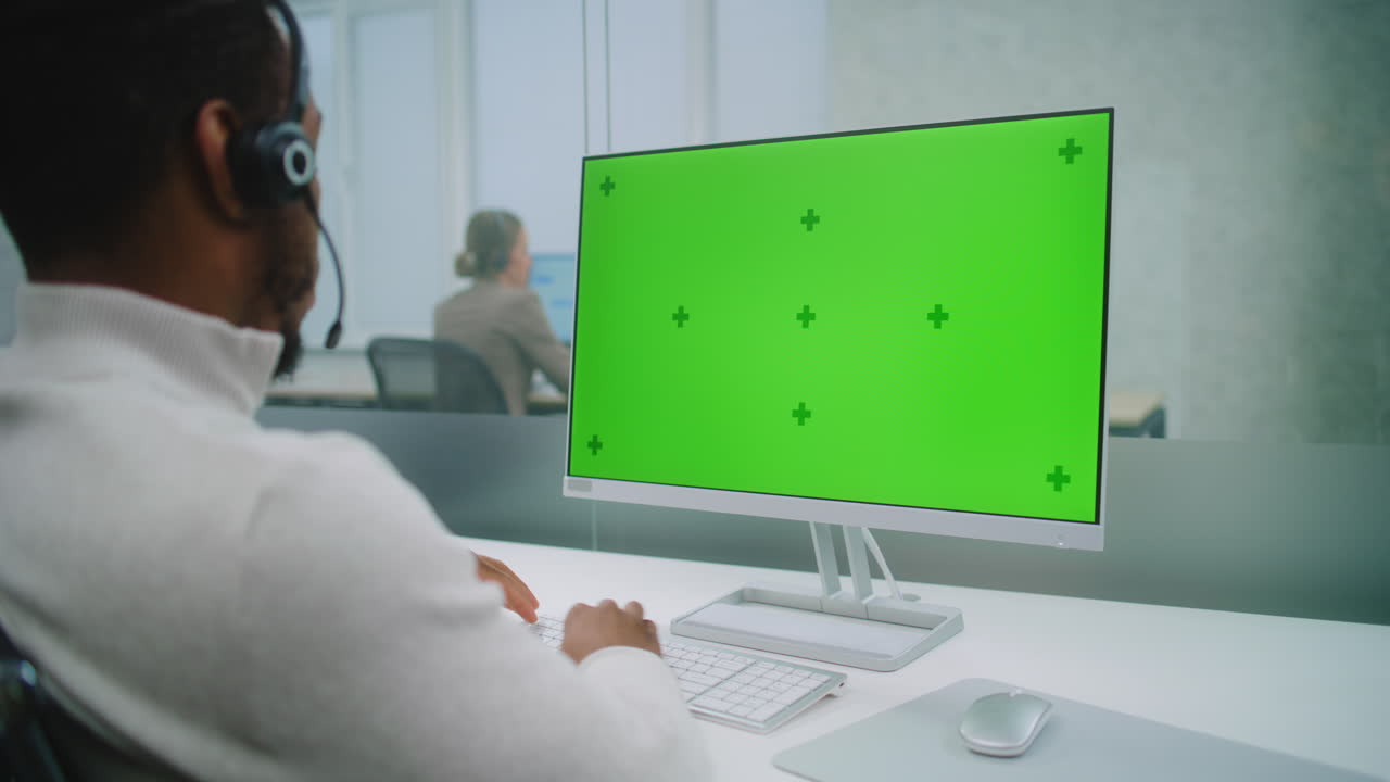 empleado del centro de llamadas trabajando en una computadora con pantalla verde