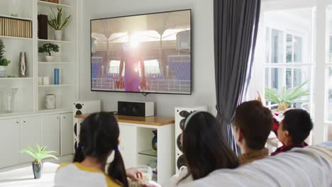 행복 한 가족 이 집 에서 함께 앉아 tv 에서 스포츠 이벤트 를 시청 하고 있는 사진