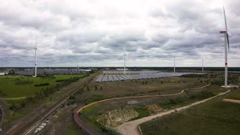 Rural-landscape-with-solar-panels-and-turbines-in-Belgium,-aerial-view