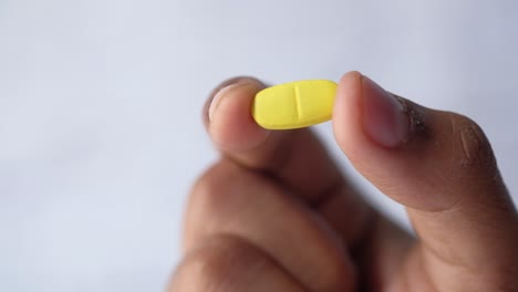 close-up of a hand holding a yellow pill