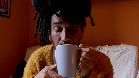 Porträt-Eines-Gutaussehenden-Mannes-Mit-Dreadlocks-Zu-Hause,-Der-An-Einer-Tasse-Tee-Nippt