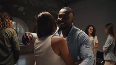 un hombre negro con una camisa azul y una chica con un peinado bob se abrazan en la terapia de grupo en un edificio de ladrillo. lograr la comprensión mutua y la comunicación agradable en la terapia de grupo como consecuencia de la resolución de problemas