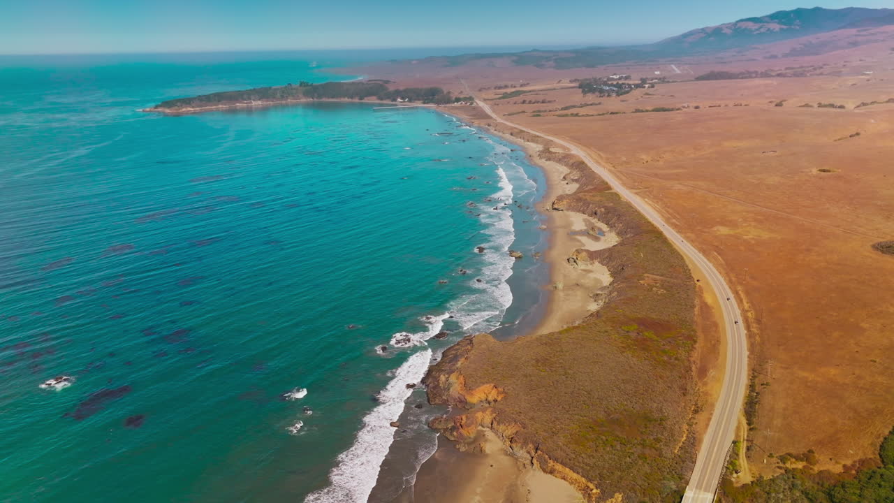 Dry deserted land bordering with blue waters of ocean. Highway through the coastline of Morro Bay, California, USA. Top view.