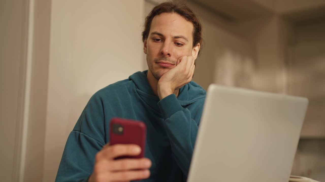 hombre usando teléfono inteligente y computadora portátil en casa