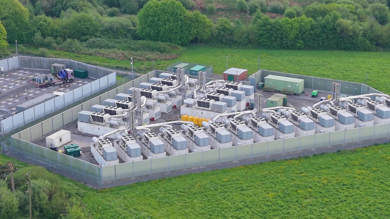 Modern Gas Peaking Plant with exhaust stacks, generators, cooling systems with BESS Battery System under Construction. Facility provides rapid-response electricity to the grid during peak demand. UK.