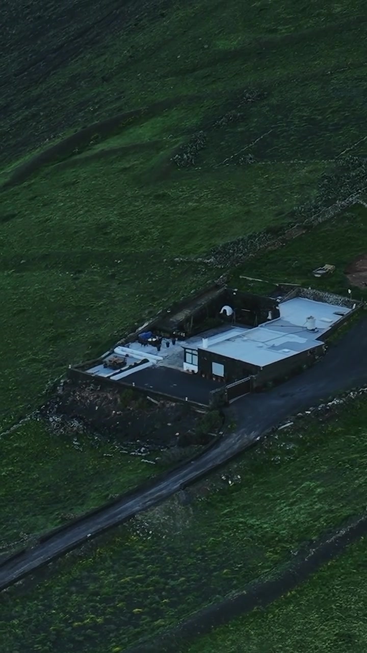 Udsigt til et hus på Lanzarote, Spanien, omgivet af grønne marker og bakker