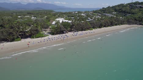 Sonnenschirme-Am-Ufer-Des-Four-Mile-Beach-Im-Sommer-In-Port-Douglas,-Queensland,-Australien---Pullback-Aus-Der-Luft