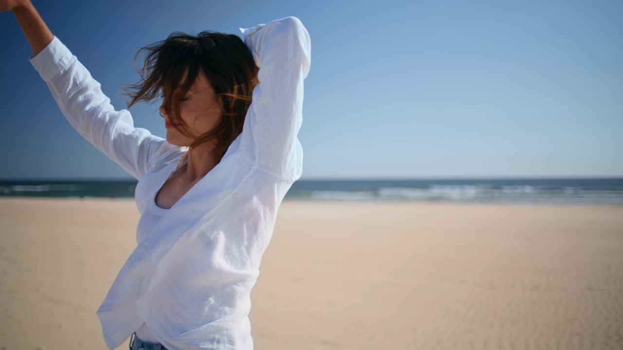 Carefree lady relaxing sea shore raising arms to clear blue sky alone closeup