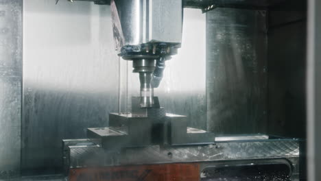una máquina cnc trabajando en una paz de metal que se enfría con chorros de agua