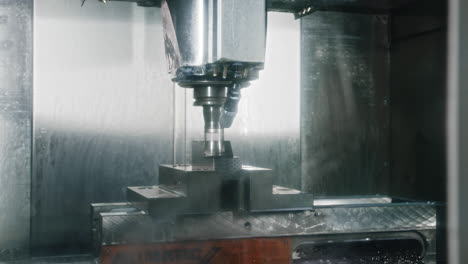 a cnc machine working on a peace of metal being cooled with water jets