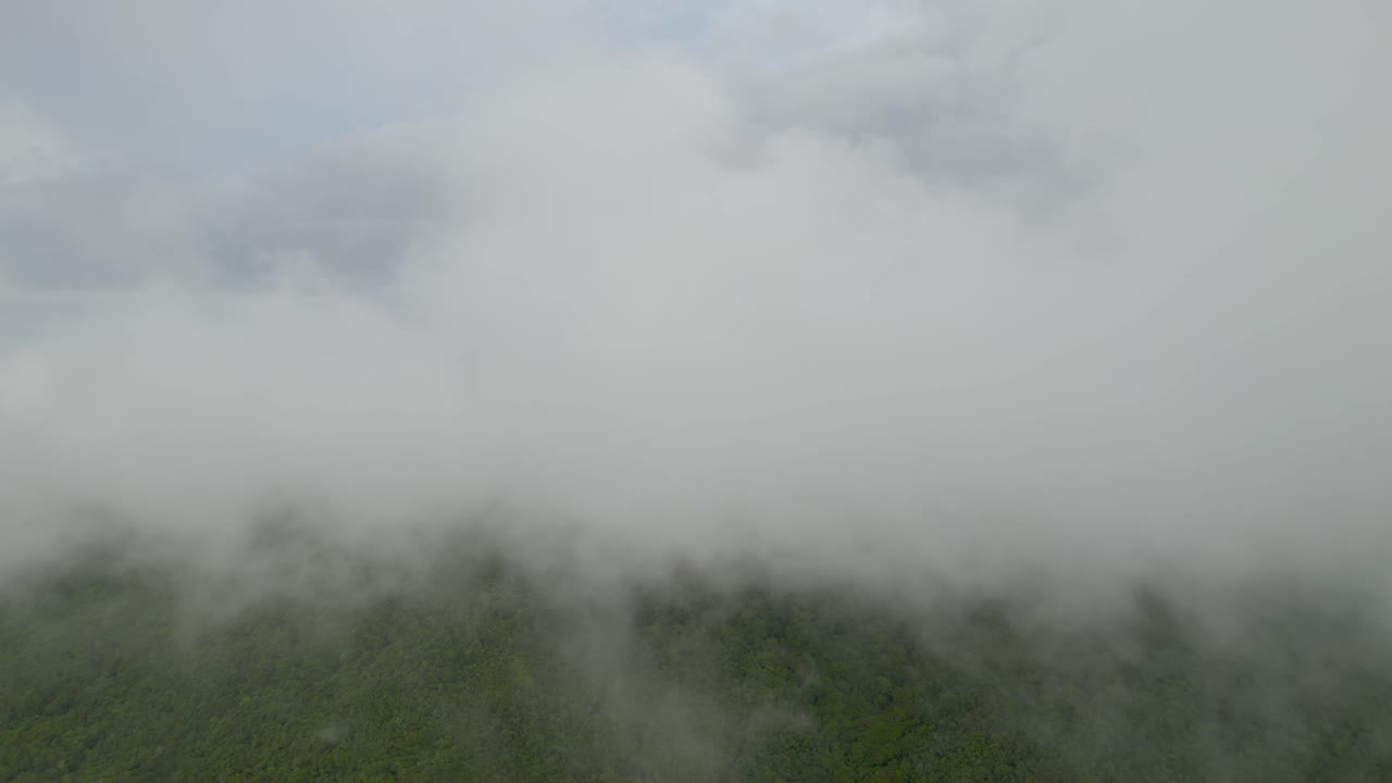 Dolly inn slowly with drone in middle of clouds and over mountains at a foggy morning in Colombia