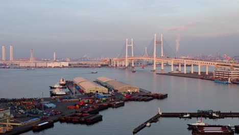un puerto bullicioso con un puente llamativo al atardecer, actividad del puerto vibrante, vista aérea