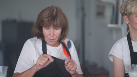 an old retired woman paints a picture together with friends. an elderly group of friends and a senior woman are drawing pictures together.